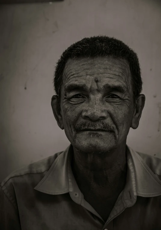 an old man in shirt standing next to a wall