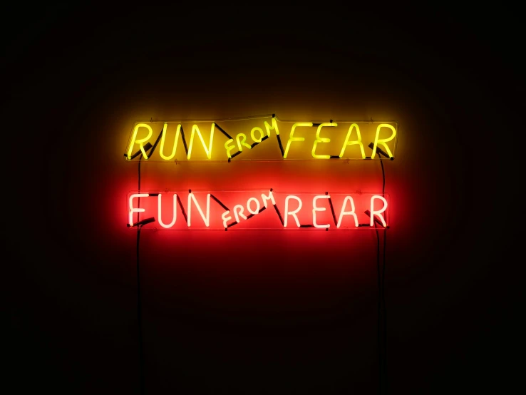 the words run or fear written on a neon sign