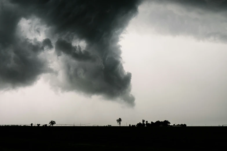 a very large cloud hangs over a field