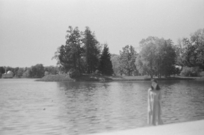 a person standing next to water with trees in the background