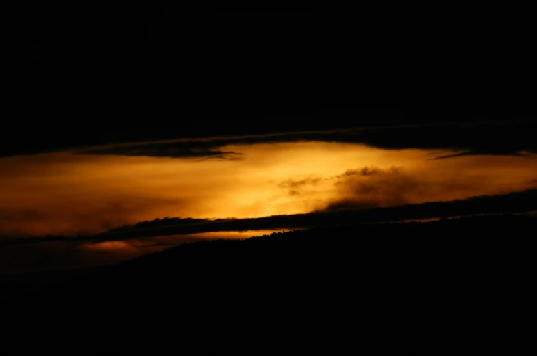 sun shining through the cloud cover in dark sky