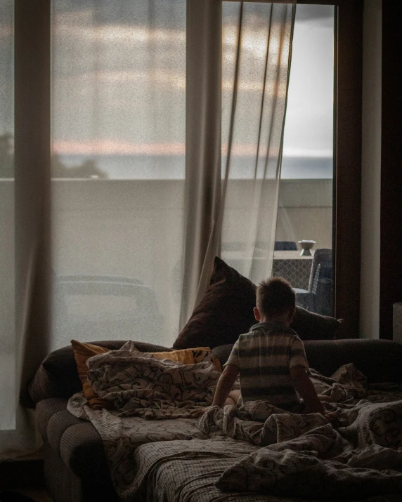a child looking out a window at an ocean