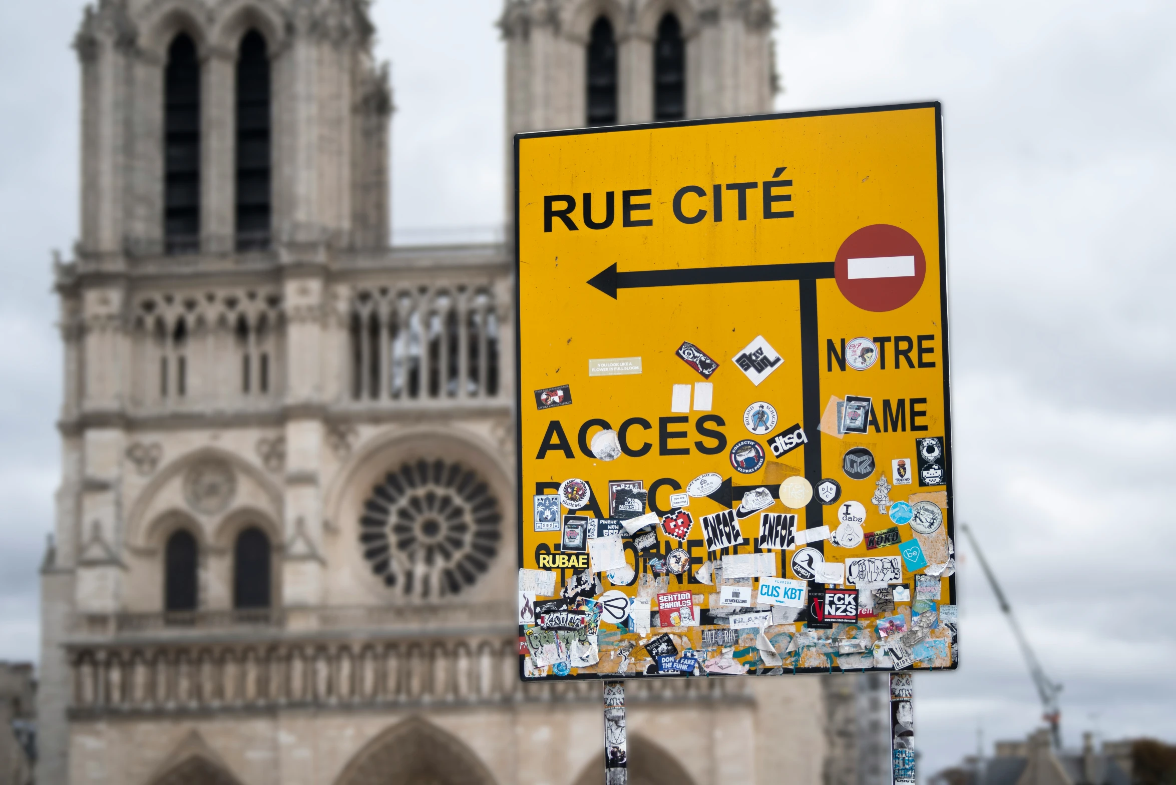 a yellow sign with black letters is beside a large tower