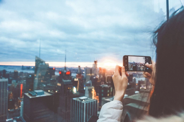 person taking a picture from top of a building at sunset