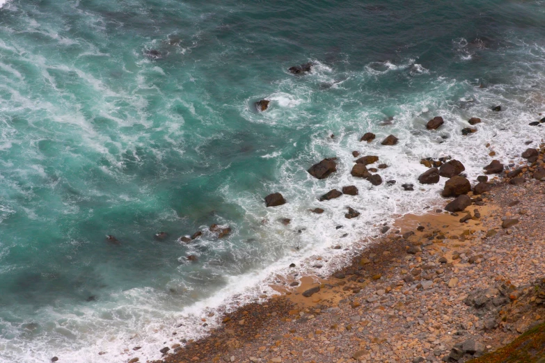 waves crashing into a rocky beach area with an umbrella