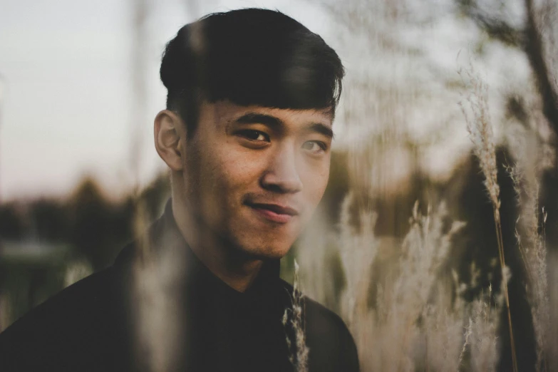 a close up of a person standing next to some tall grass