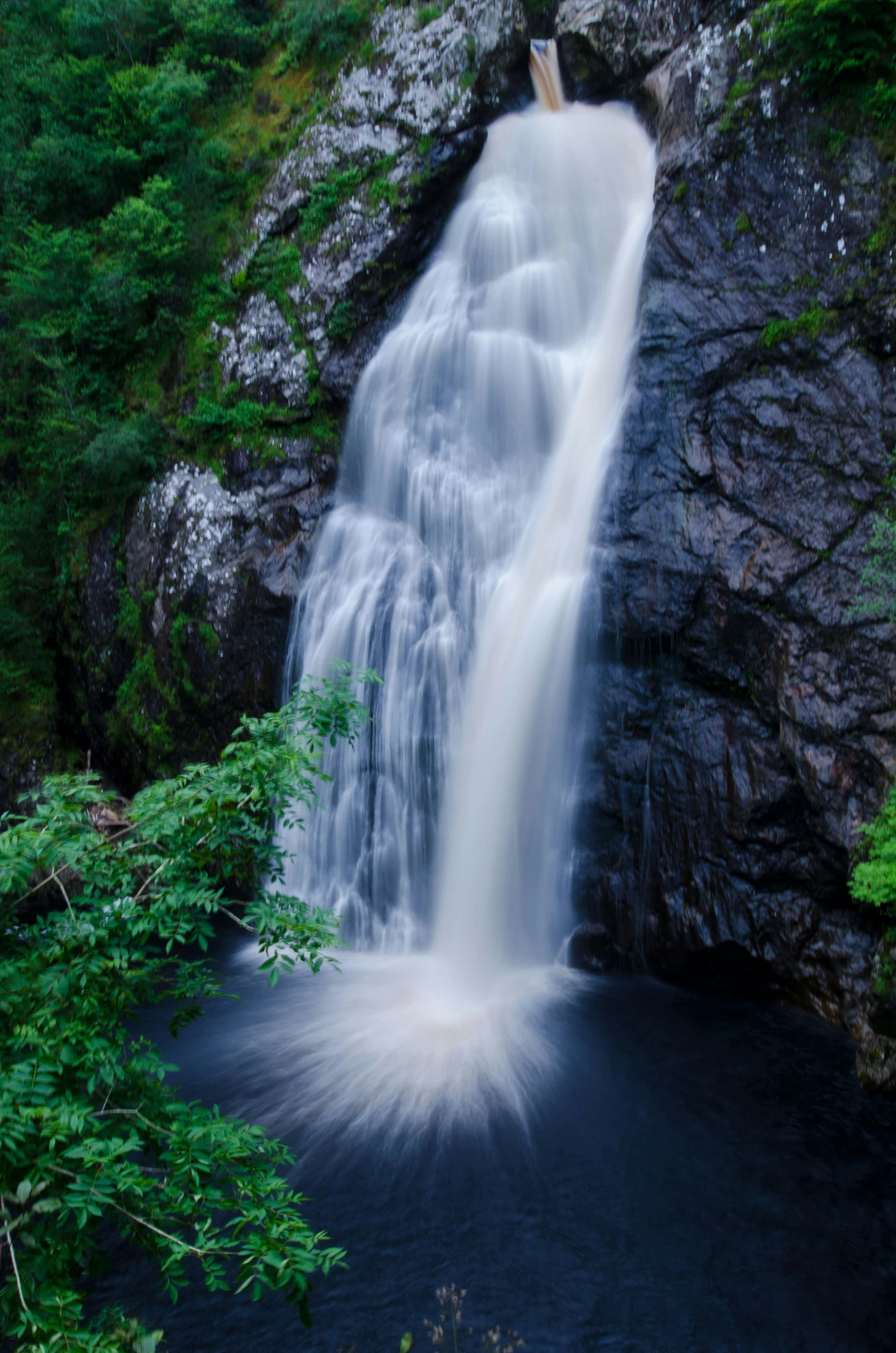 a very tall waterfall in the middle of a forest