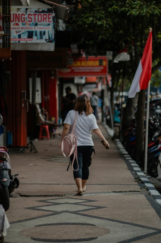 a woman walking down the sidewalk of a shopping area