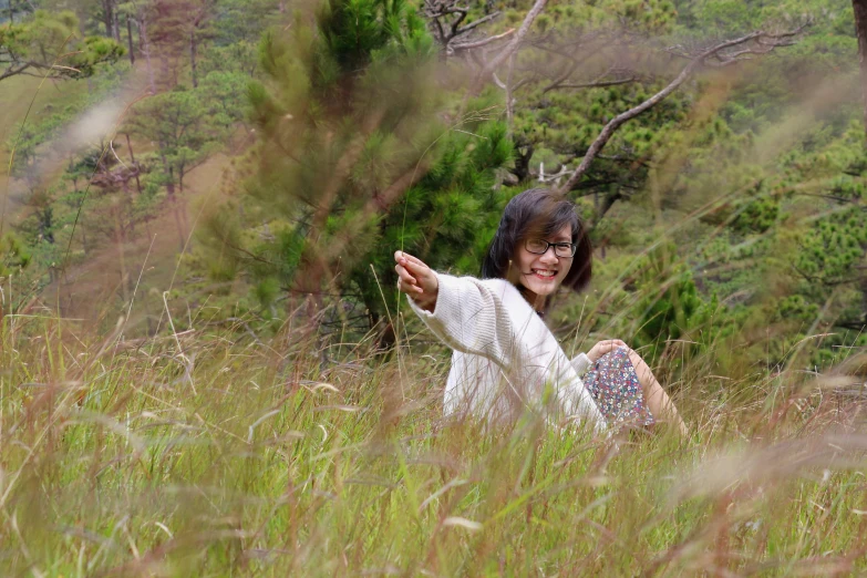 a woman is posing for a po while sitting in the tall grass