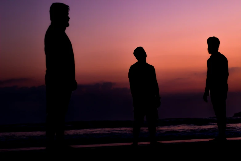 four people are standing in the dark near a body of water