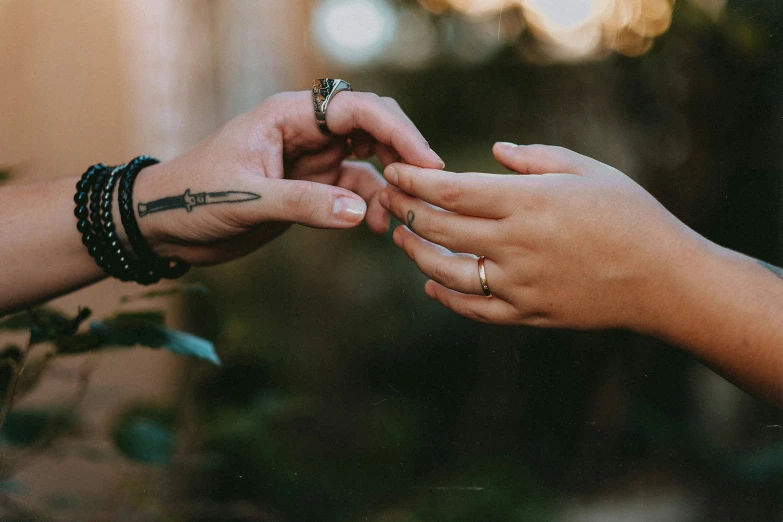 two people putting rings on each other while holding hands