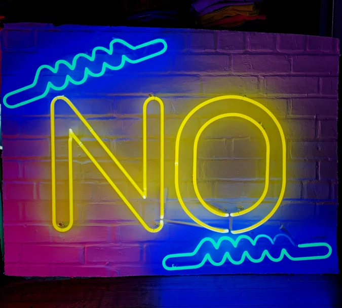 a neon sign for no on the side of a brick wall