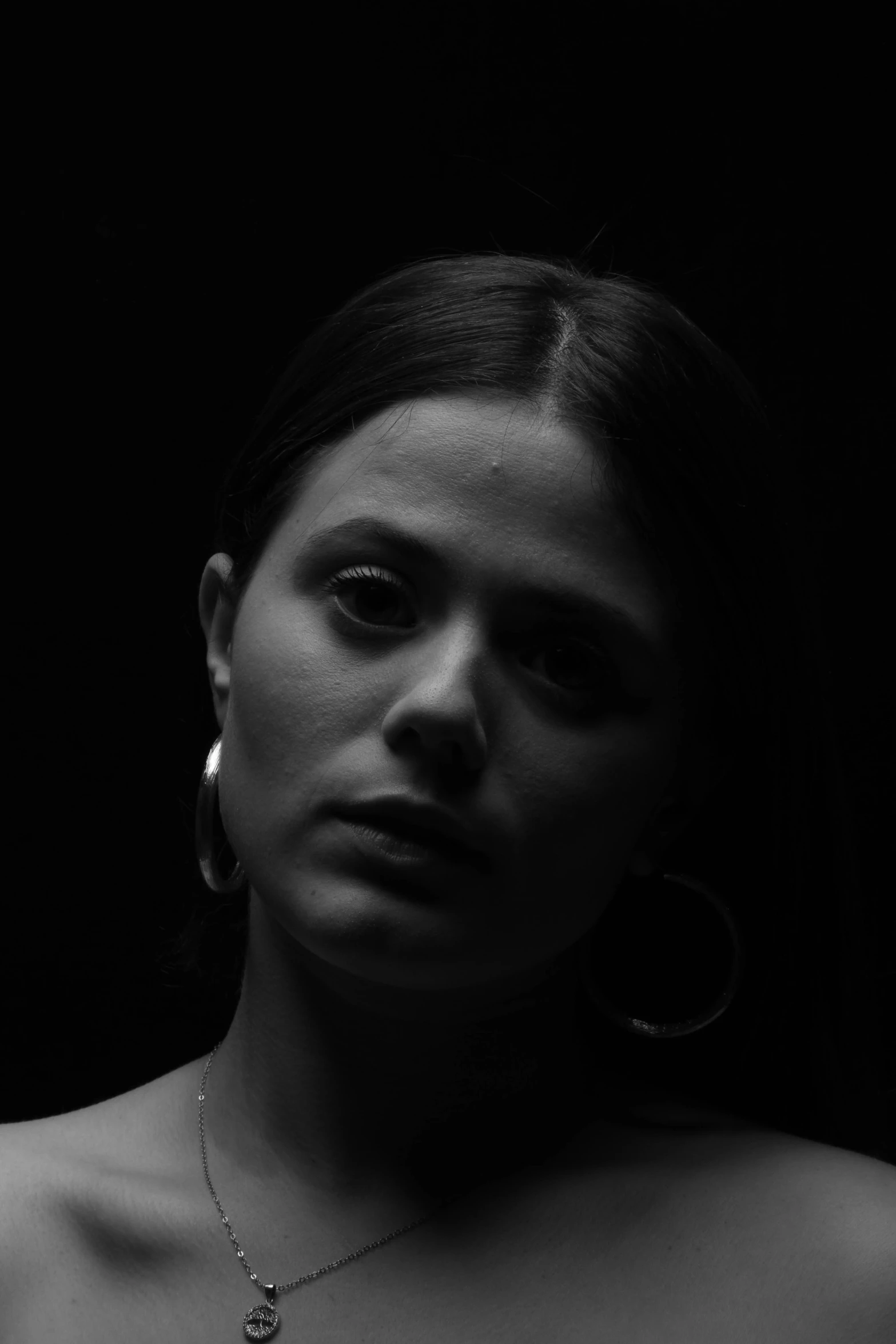 a woman wearing large hoop earrings with dark background