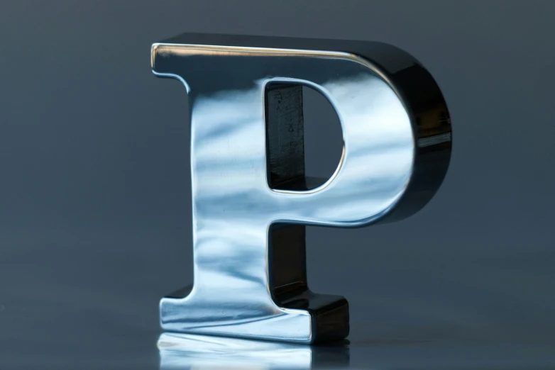 a chromed metal letter p in the middle of a gray background