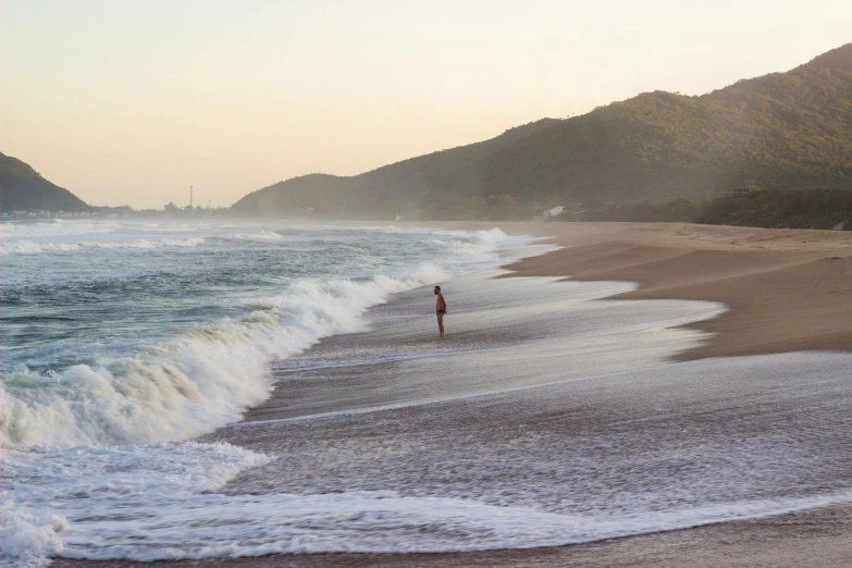 there is a person walking in the water at the beach