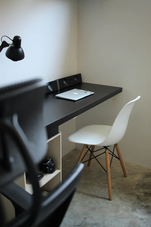 a small black desk with a lamp next to it