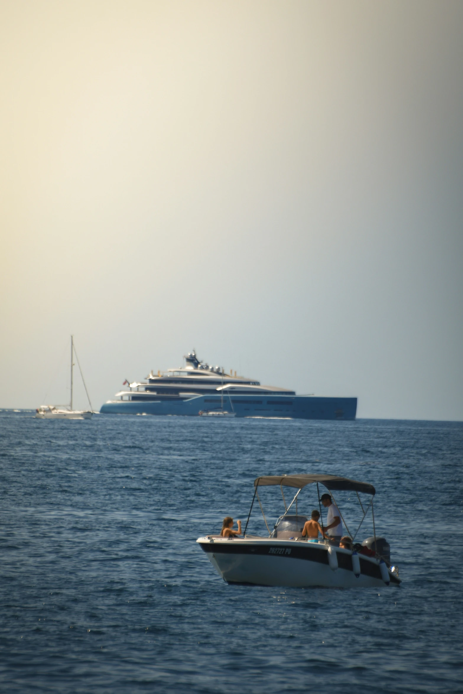 several cruise boats traveling in the ocean near a large ship