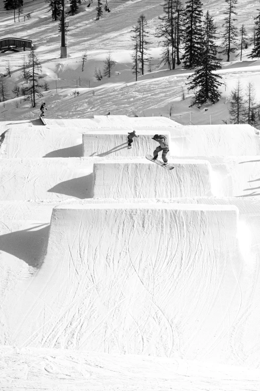 two snowboarders performing tricks at the top of a ski slope