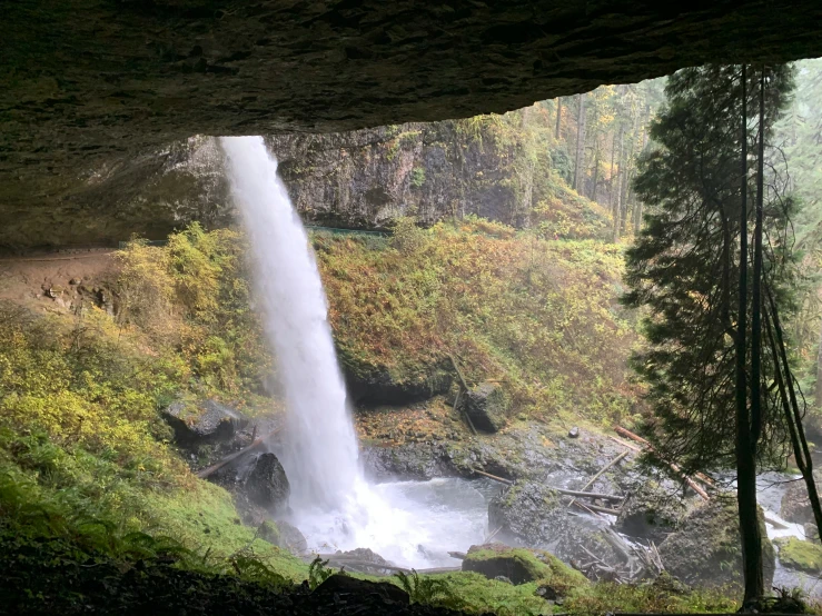 a stream gushing from under a cliff at a waterfall