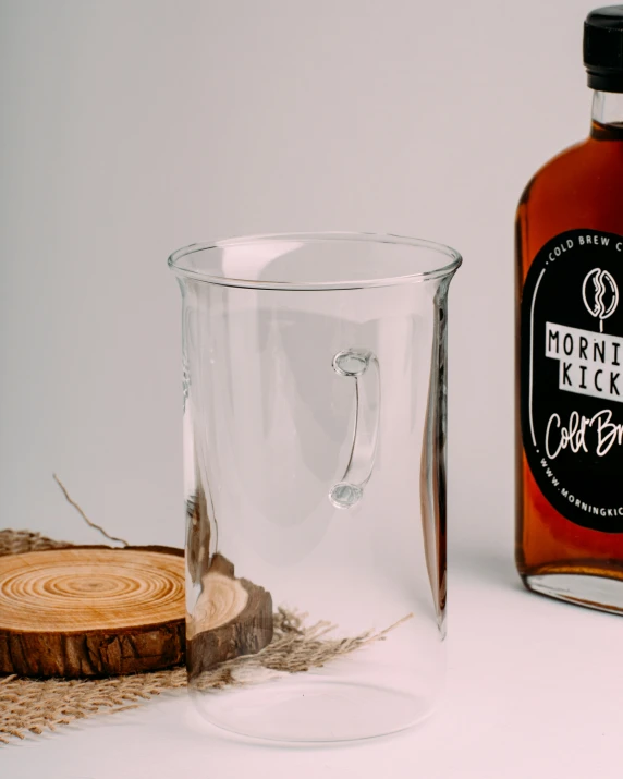 a clear glass next to a bottle of booze