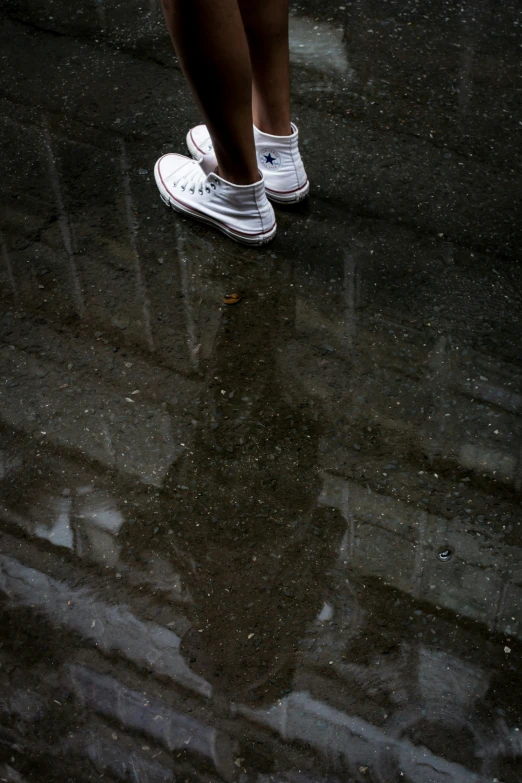 two women walk on wet surface under an umbrella