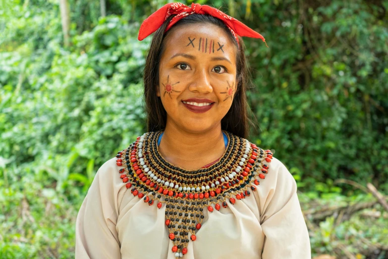 a native woman stands in front of a wooded area