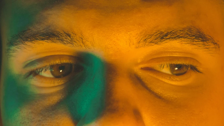 two people's eyes, one of them is green and yellow, are shining brightly in the background