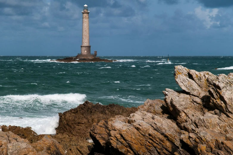 a lighthouse surrounded by rough seas on a cloudy day