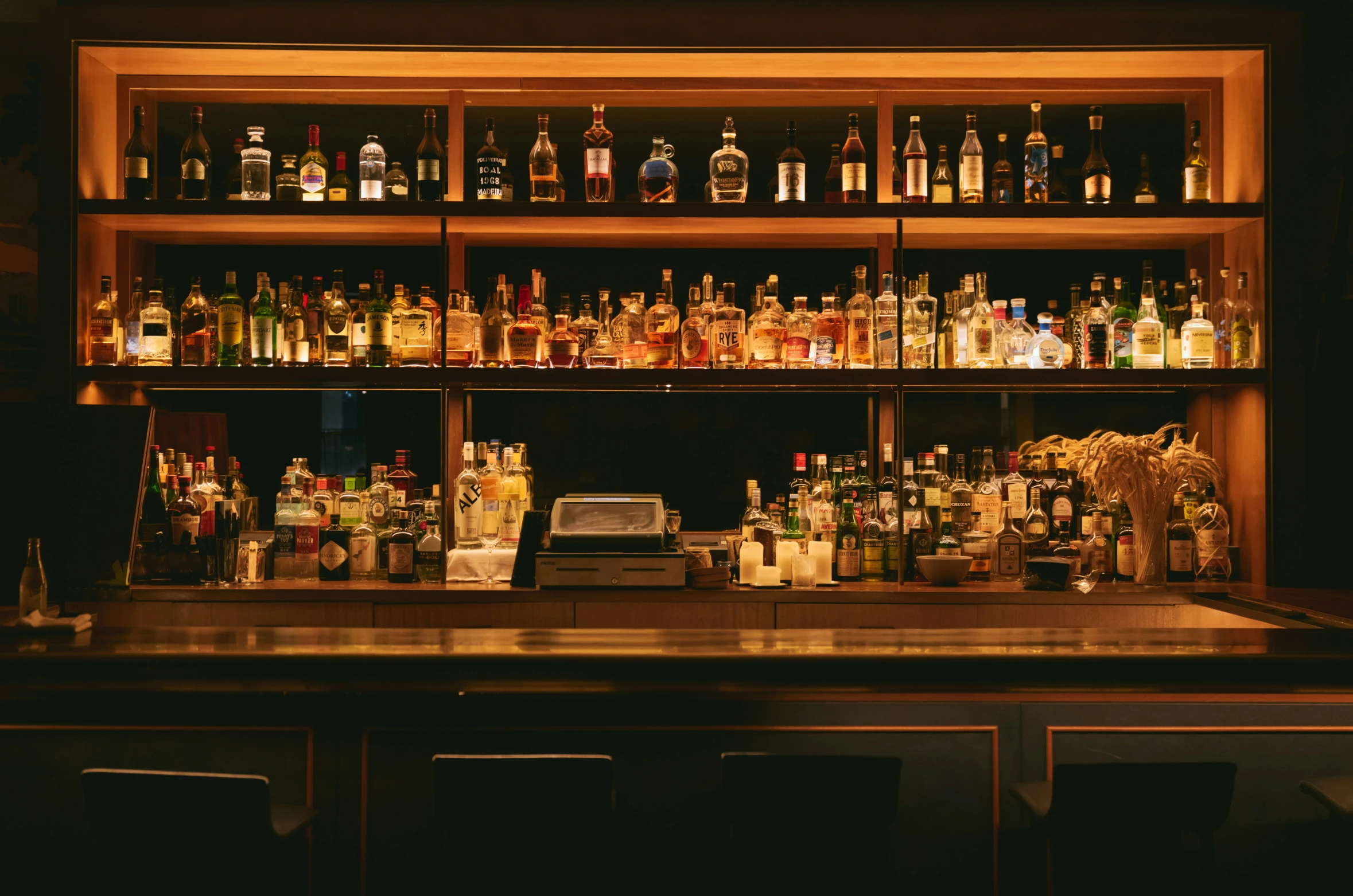 a wall filled with lots of bottles and jars on top of a bar