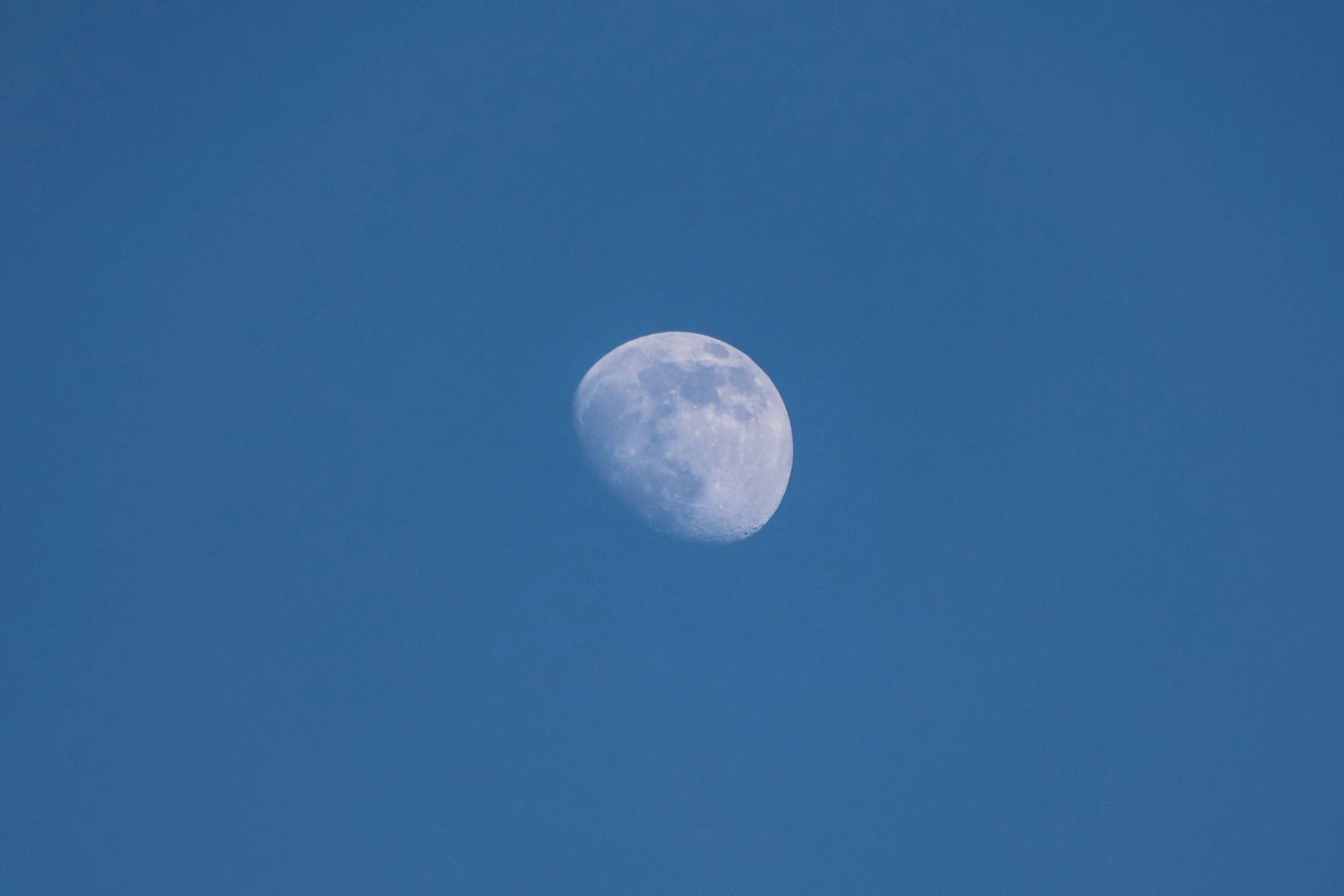 the full moon is just beginning to rise in the blue sky