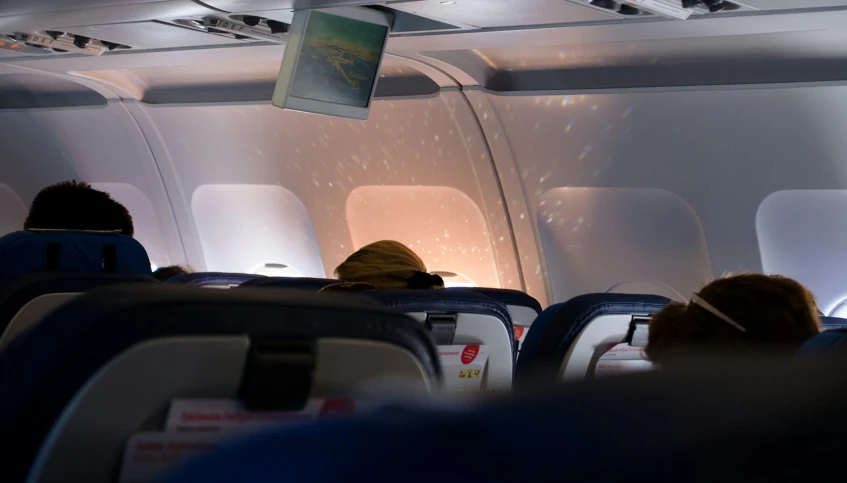 the aisle in a airplane is very empty with people sitting around it