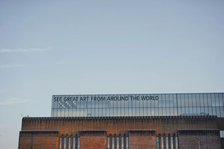 an outside view of a large brick building with a large, glassed sign on top