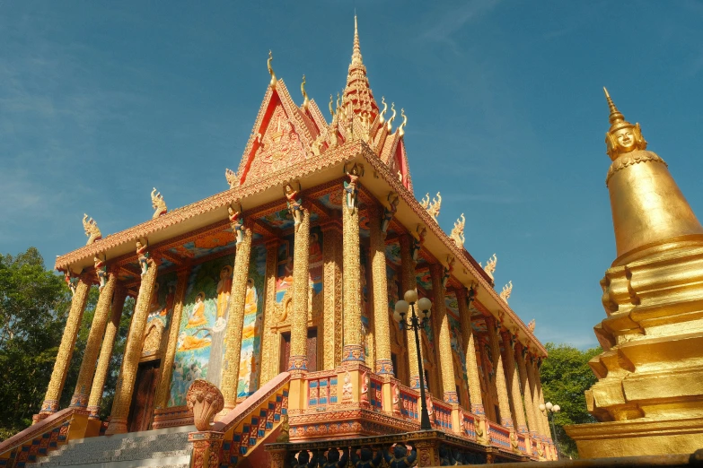 gold and red building with a statue below it