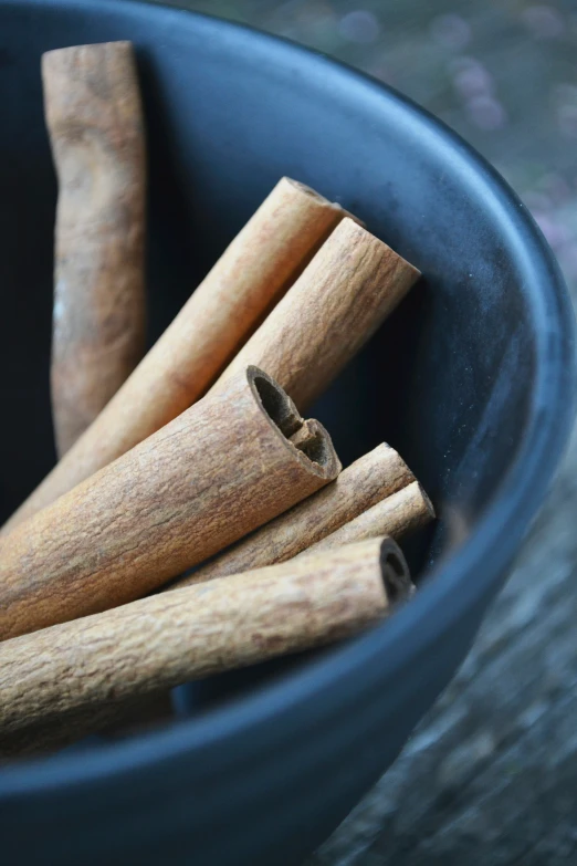 a blue bowl filled with cinnamon sticks on top of a table