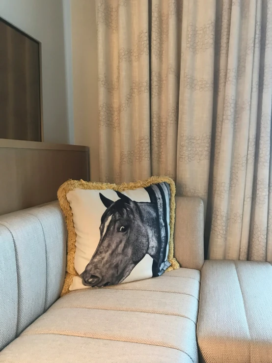 the horse throw pillow is sitting on a small couch