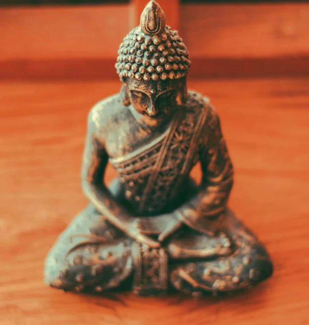 a buddha statue sitting on a wooden floor