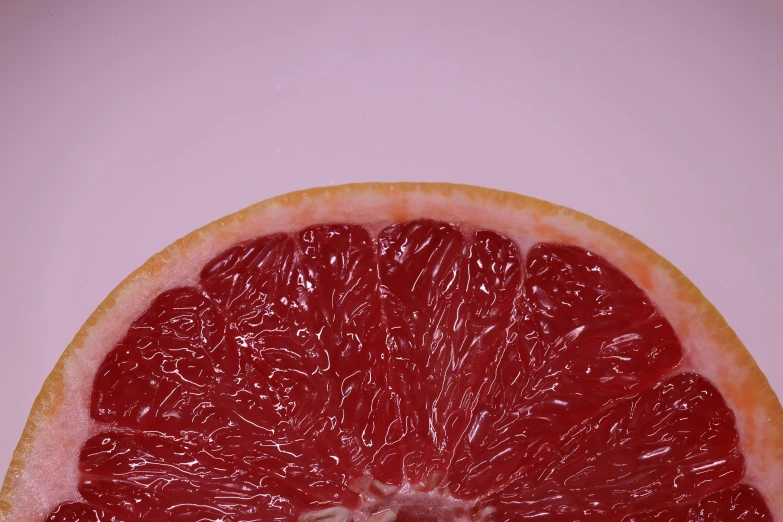 a gfruit cut in half and sitting on a pink surface