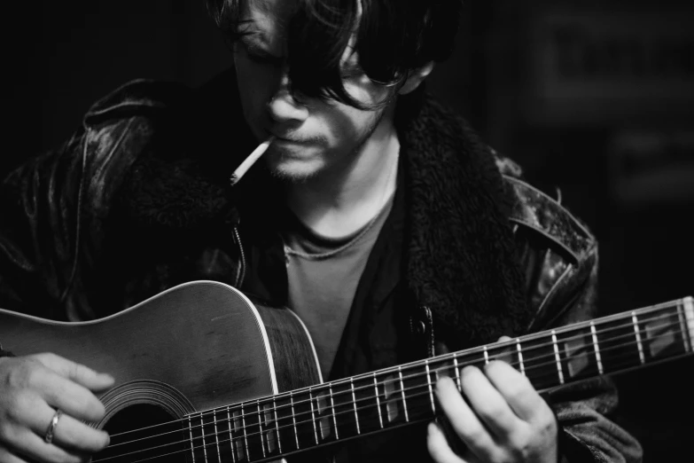 a man that is playing a guitar with a cigarette