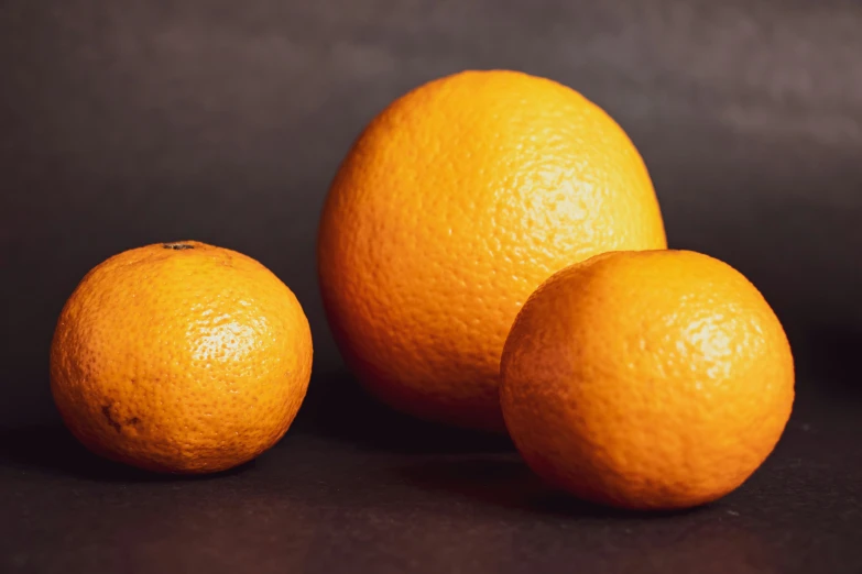 a group of five oranges on a black table