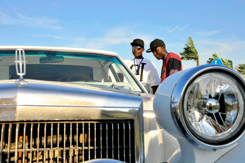 two men standing by a white car on a clear day