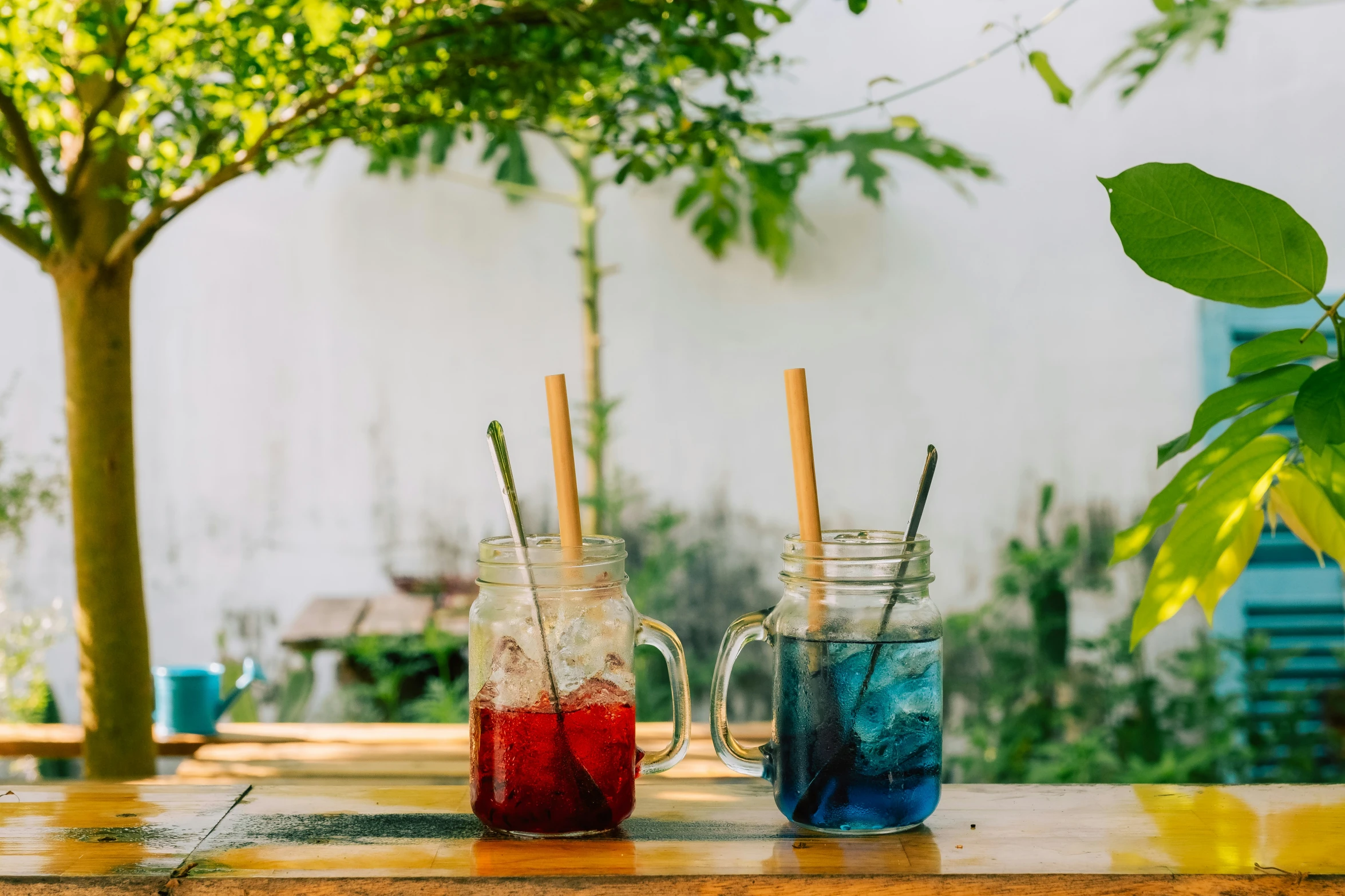 three colorful drink in bottles on table outside