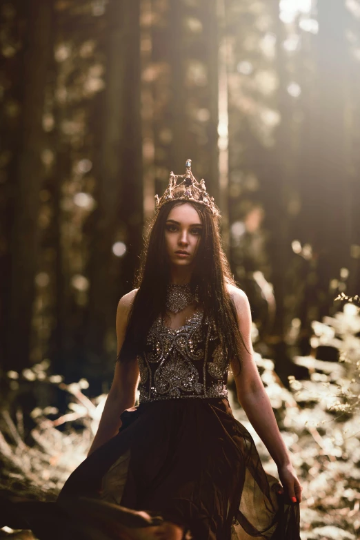 a woman in a dress wearing a crown is standing among tall trees