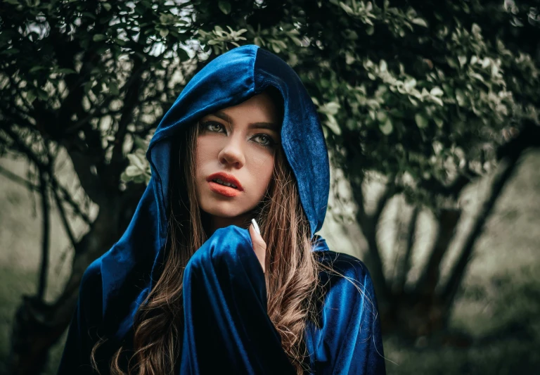 a girl in blue sitting under a tree