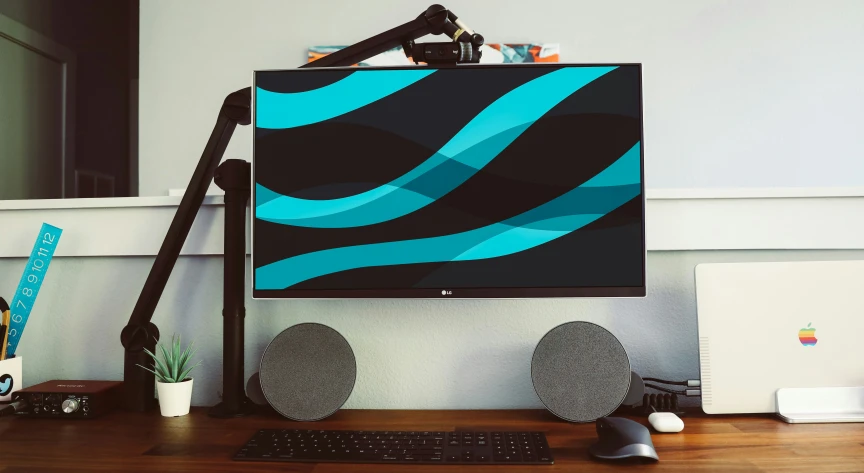 a desk with an apple computer and speakers