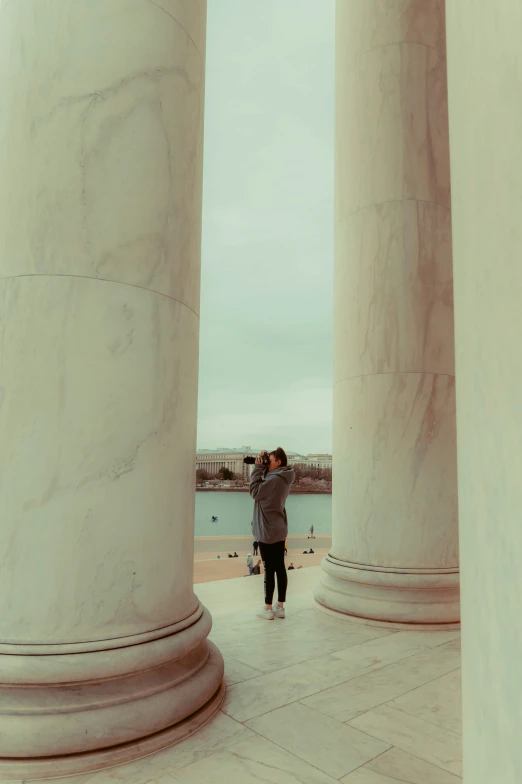 a man is taking a po of the sea through some white pillars