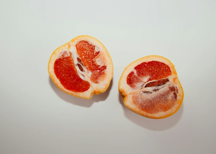 a close up of two  orange halves on a white surface