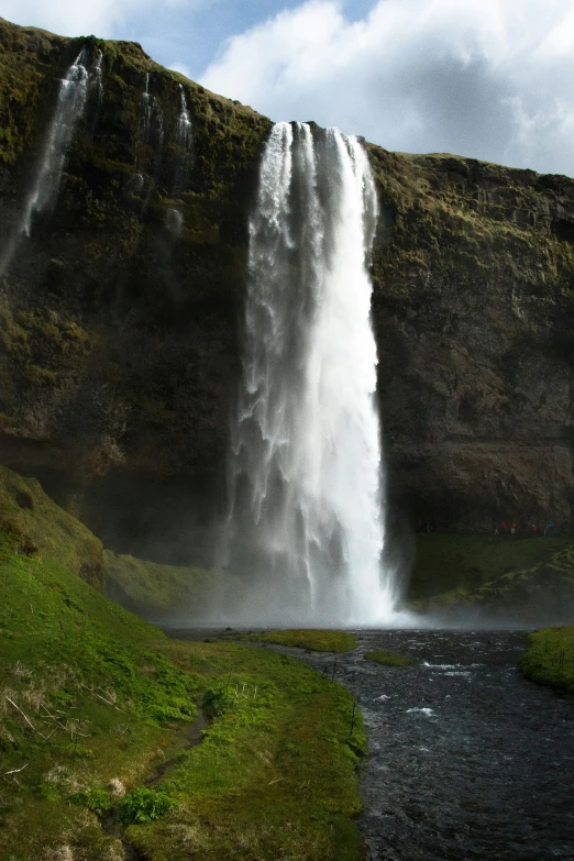 a large waterfall near the ocean with a body of water below