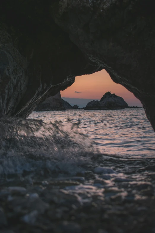 view of sunset through the cave at the beach