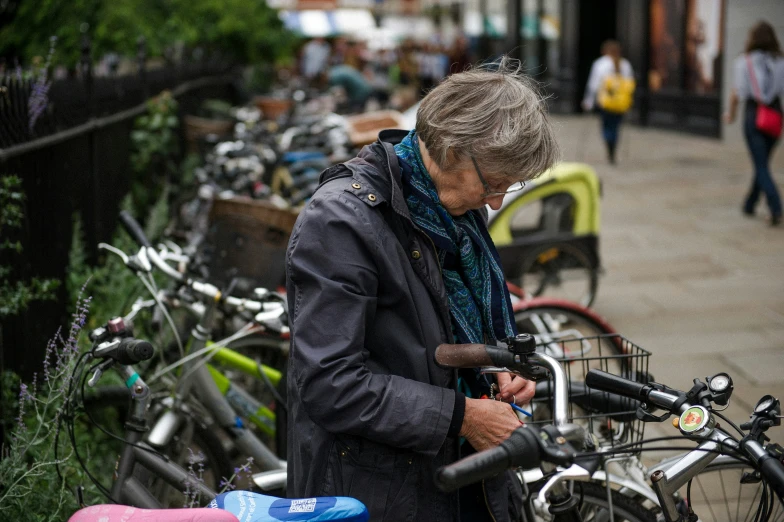 a woman stands next to a row of bicycles while checking her phone