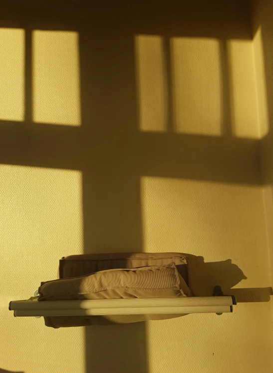 a light casts on a beige wall with a shadow cast by pillows